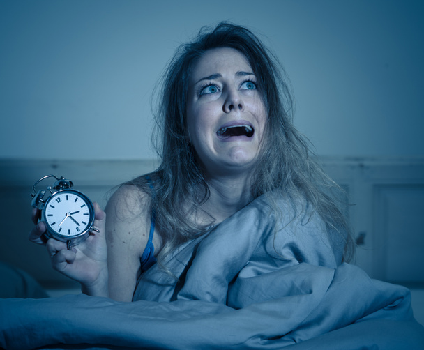 Sleepless and desperate beautiful caucasian woman awake at night not able to sleep, showing clock, feeling frustrated and worried suffering from insomnia in sleep disorder concept. - Фото, зображення