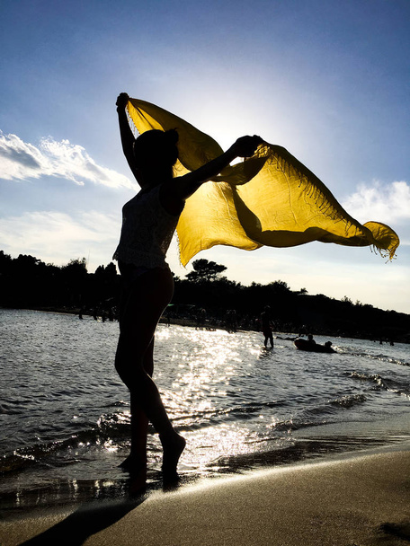 Dziewczyna sylwetka z żółtym szalik pod zachód słońca - Zdjęcie, obraz