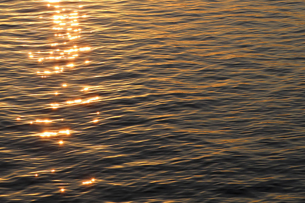 Tekstuuri aaltoilu vedessä kirkas aurinko kohokohtia auringonlaskun aikana
. - Valokuva, kuva