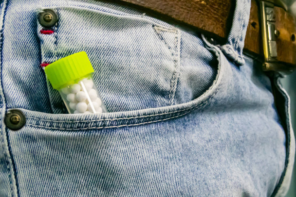 Concepto de salud homeopática - Botella de medicina homeopática con pastillas en el bolsillo de un Jeans
 - Foto, Imagen