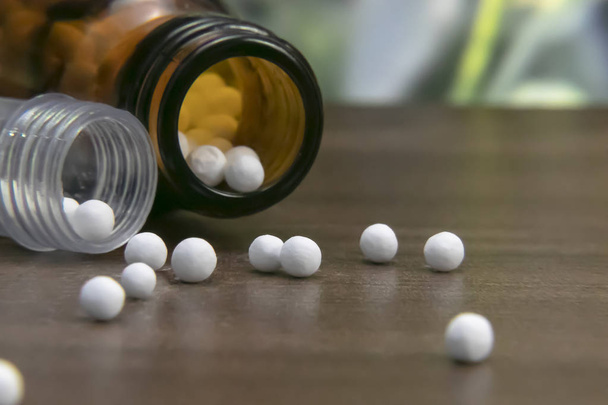 Dağınık Homeopatik granüller ve şişe ahşap arka plan üzerinde yakın. Alternatif Homeopati ilaç kavramı. - Fotoğraf, Görsel