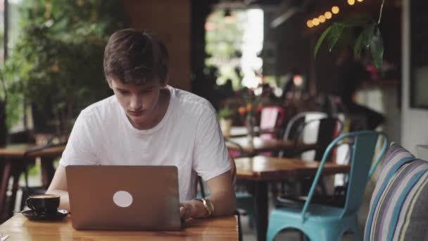 Νέος άνθρωπος σερφ ιστοσελίδα και chat, ανεξάρτητος και blogger εργάζονται ως γραφικός σχεδιαστής εσωτερικό, μοντέρνο χώρο εργασίας που κάθονται στο καφέ. Άνοιγμα φορητού υπολογιστή στο εστιατόριο. - Πλάνα, βίντεο