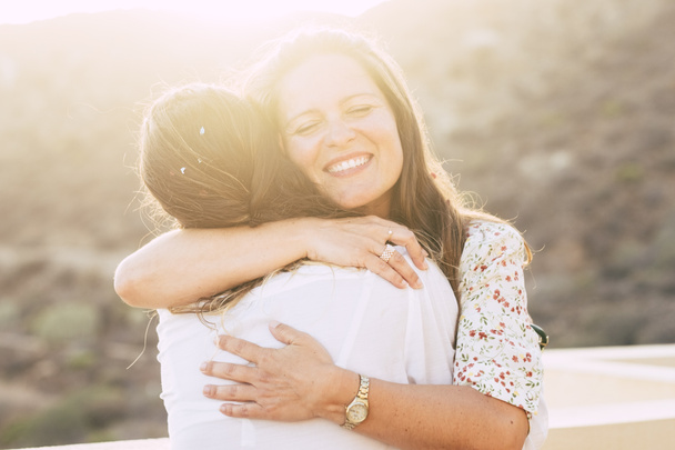 Love and friendship concept with couple of women young friends hugging and smiling with love - diversity for caucasian people - alternative love - sun in backlight with light effect - Photo, Image