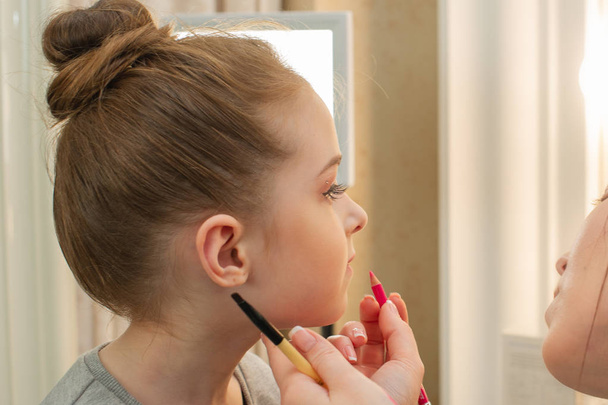 a little girl doing makeup before performing on stage. Preparation before the performance in the dressing room - Valokuva, kuva