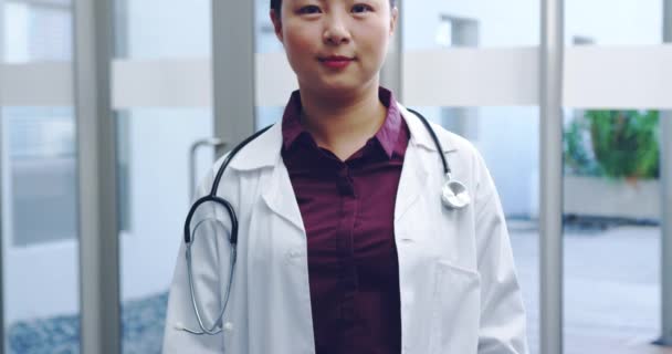 Slow motion waist up tilt shot of young female Asian doctor wearing lab coat smiling to camera 4k - Felvétel, videó