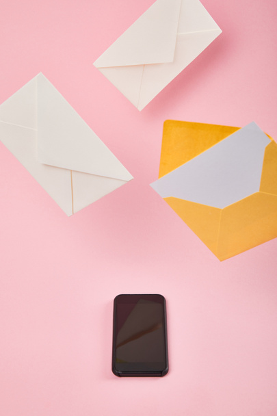 φάκελοι κοντά σε smartphone με κενή οθόνη σε ροζ φόντο - Φωτογραφία, εικόνα