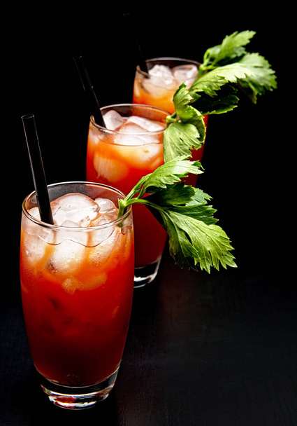 Bloody Mary cocktails with ice cubes and celery on black - Φωτογραφία, εικόνα