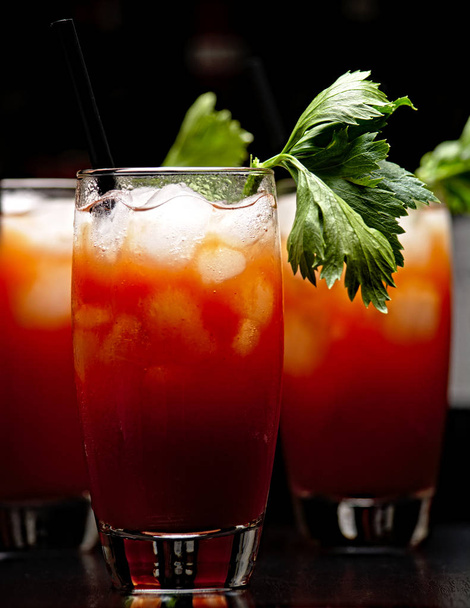 Cropped frame of Bloody Mary with ice cubes with celery in club on black - Photo, image