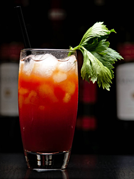 Bloody Mary with ice cubes with celery in club on black - Foto, Imagem