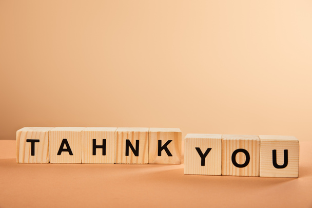 wooden cubes with thank you lettering on table isolated on beige - Photo, Image