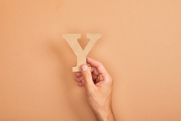 cropped view of man holding paper cut letter Y on beige background - Foto, Bild