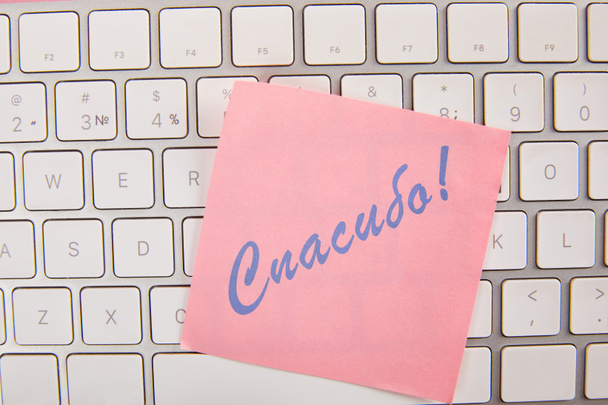 вид на розовую липкую ноту с благодарной надписью на русском языке на клавиатуре ноутбука
  - Фото, изображение