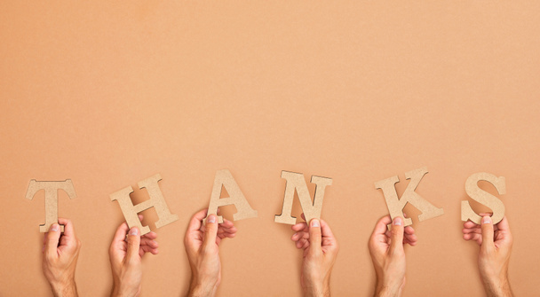 visão parcial de homens segurando palavra de agradecimento dispostos a partir de letras de corte de papel no fundo bege
 - Foto, Imagem
