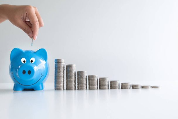 putting coin in blue piggy with coins graph, step up growing business to success and saving for retirement concept - Photo, Image