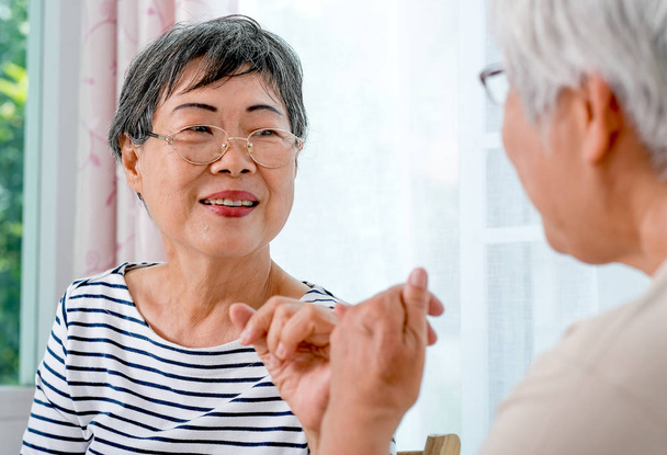 Uma mulher idosa asiática gancho uns aos outros dedo pequeno para o outro com sorrindo na frente da varanda na casa
. - Foto, Imagem