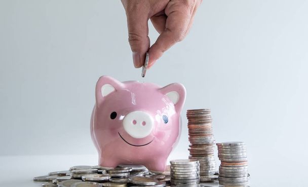рука положить монету в розовый копилку с кучей монет, шаг вперед растущего бизнеса к успеху и сбережений для пенсионного концепции
 - Фото, изображение