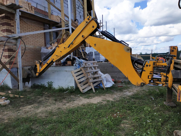 掘削機は建設中の建物の周りにダーツを掘ります. - 写真・画像
