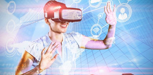 Female use virtual reality headset against composite image of technology interface - Photo, image