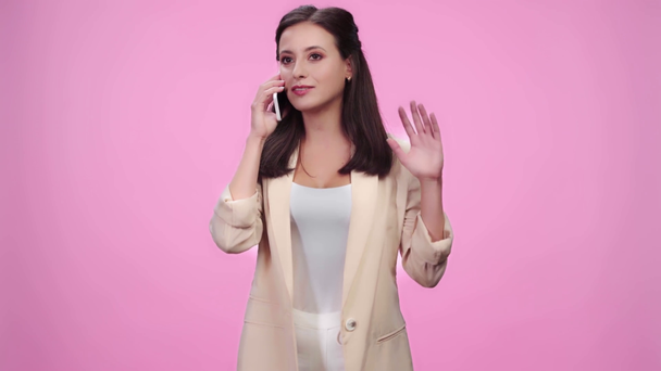 beautiful girl talking on smartphone, laughing and gesturing isolated on pink - Materiał filmowy, wideo