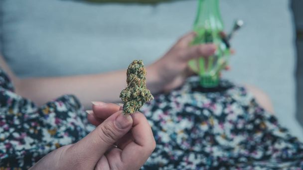 The young person hold in his hand medical marijuana buds and bon - Foto, imagen