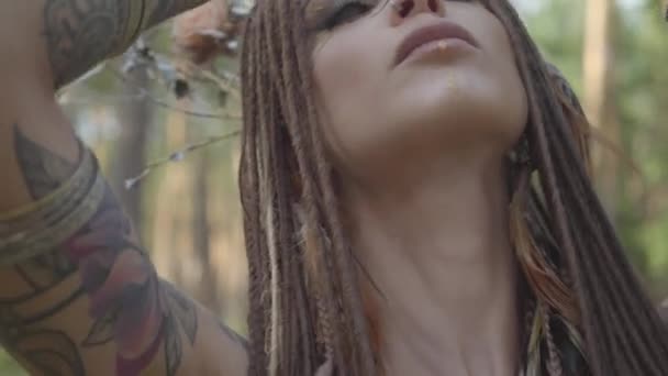 Ελκυστική Δρυίδα ή νεράιδα του δάσους με Αφρο-πλεξούδες και τατουάζ στο σώμα που χορεύει με μια όμορφη στολή. Το αρχαίο τελετουργικό του δάσους. Απόδοση της χορευτή στο δάσος - Πλάνα, βίντεο