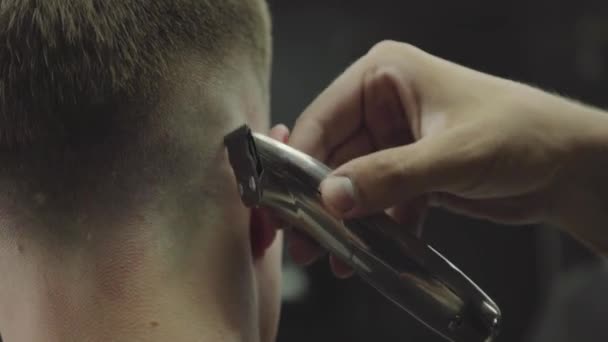 Male haircut with electric razor. Close up of hair trimmer hairstyle. Barber makes haircut for client at the barber shop by using hairclipper. Man hairdressing with electric shaver. Handheld shot. 4K. - Filmagem, Vídeo