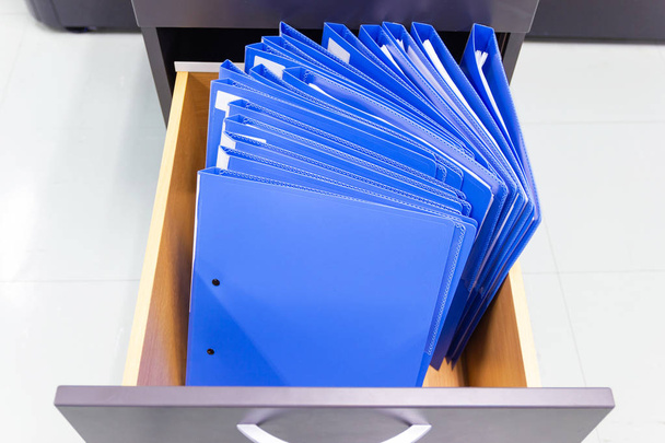 Документы голубой папки В шкафу хранения файлов контрактов
. - Фото, изображение