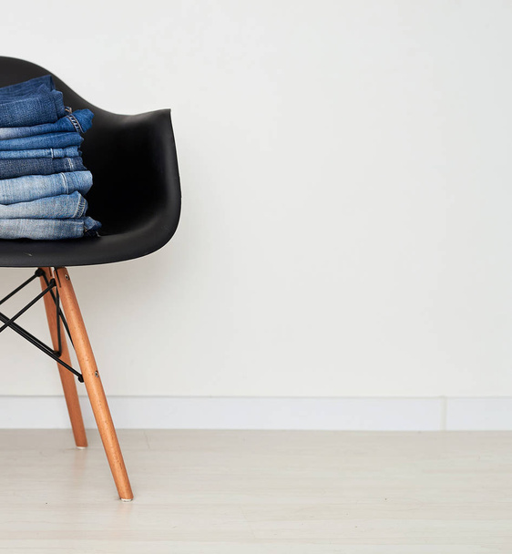 Jeans clothing stacked on a plastic chair - Фото, изображение