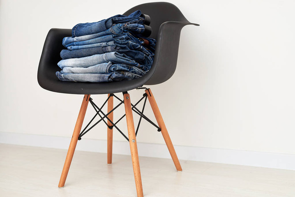 Jeans clothing stacked on a plastic chair - Фото, зображення