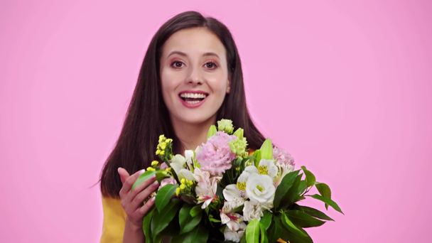 krásná dívka čichá květiny, dívá se na kameru a usmívá se izolovaná růžová - Záběry, video