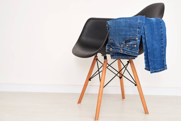 Jeans clothing stacked on a plastic chair - Foto, afbeelding