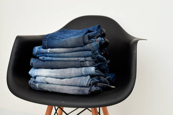 Jeans clothing stacked on a plastic chair - Foto, Bild
