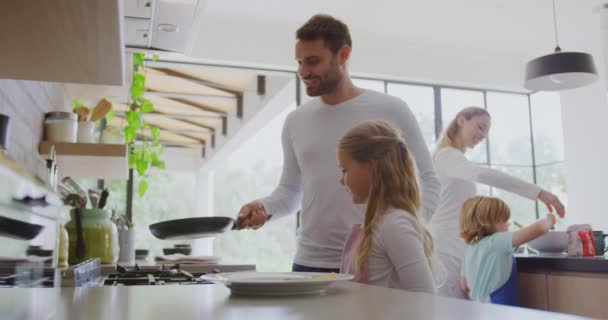 Side view of Caucasian family preparing food in kitchen at home. Father holding pan 4k - Filmagem, Vídeo