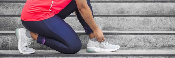 Женщина завязывала шнурки на кроссовках перед тренировкой. Runner
 - Фото, изображение