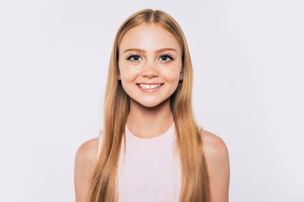 Close up portrait of happy attractive and cute blonde little girl with long hair while she is posing  isolated in studio and smiling - Photo, Image
