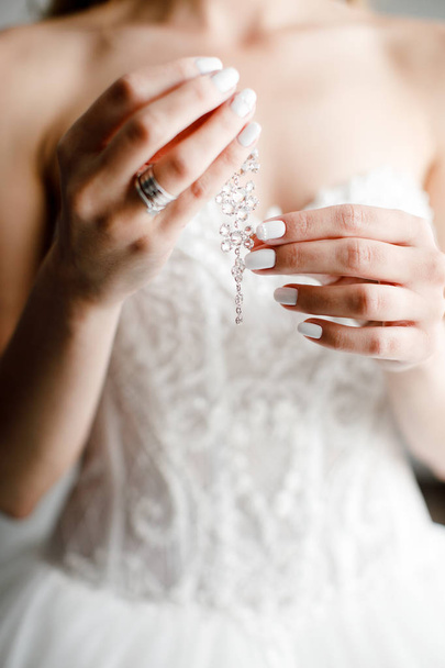 the bride is holding earrings close up. - Φωτογραφία, εικόνα