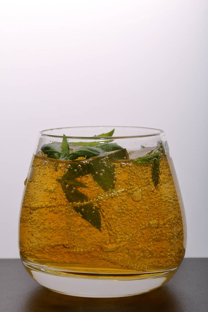 Refreshing drink with gas bubbles. Nalit in a transparent glass. It laid crushed ice. Decorated with mint leaves. - Photo, Image