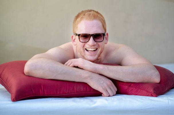 Νέοι κόκκινα μαλλιά άνθρωπος με γυαλιά ηλίου χαμογελά στο σαλόνι - Φωτογραφία, εικόνα