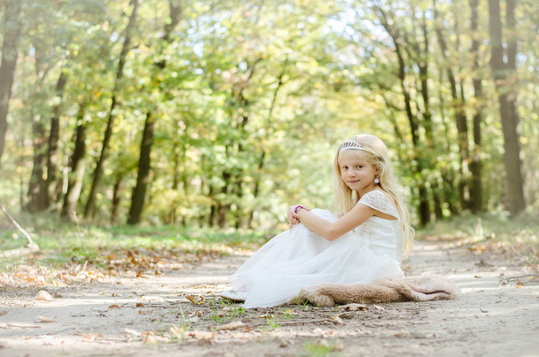 романтический ребенок сидит в платье принцессы под деревьями
 - Фото, изображение