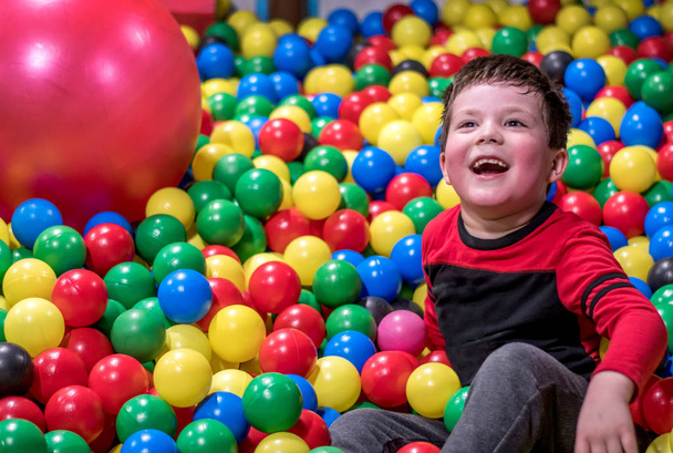 смеющийся мальчик в колоритной яме для шаров
 - Фото, изображение