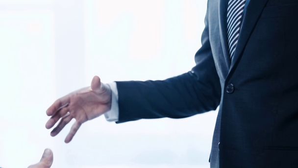 スーツを着た2人のビジネスマンがオフィスで握手をする様子を見る - 映像、動画