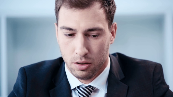 slow motion of handsome, shocked businessman sitting at workplace in office - Filmmaterial, Video