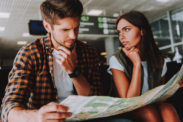 Thoughtful man and woman are planning holiday in airport - Foto, afbeelding