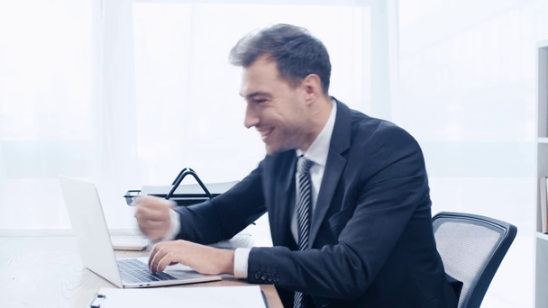knappe zakenman typen op laptop, glimlachend en toont winnaar gebaar - Video