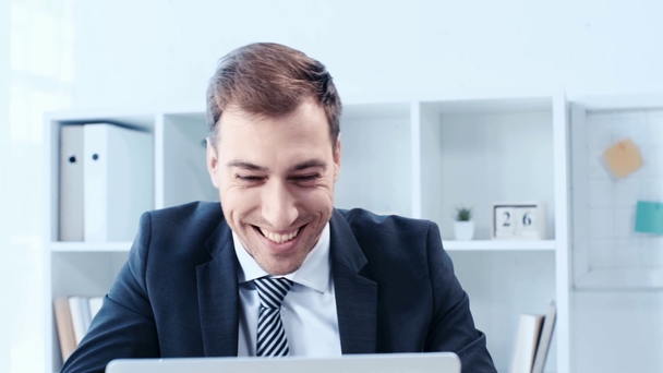 glücklicher Geschäftsmann zeigt Siegergeste, während er Laptop im Büro benutzt - Filmmaterial, Video