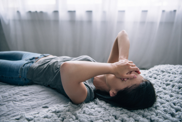 depressed woman lying on bed and covering face at home - Photo, Image