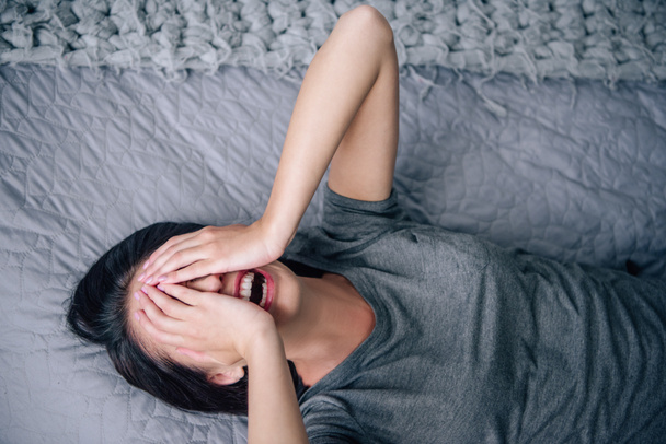 mujer deprimida cubriendo la cara y llorando mientras está acostada en la cama en casa
 - Foto, Imagen