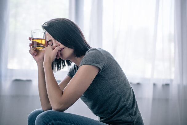 mujer sola disgustada con vaso de whisky en casa
 - Foto, Imagen