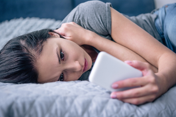 einsame, traurige Frau im Bett mit Smartphone im Schlafzimmer - Foto, Bild