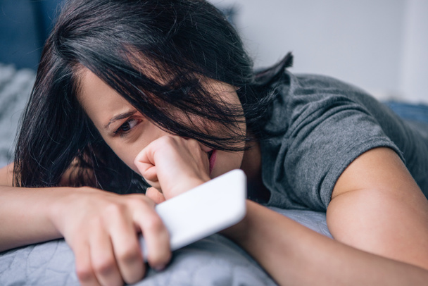 одинокая депрессивная женщина плачет на кровати со смартфоном в спальне
 - Фото, изображение